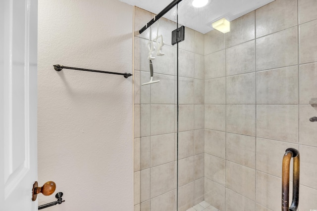 full bath featuring a shower stall and a textured wall