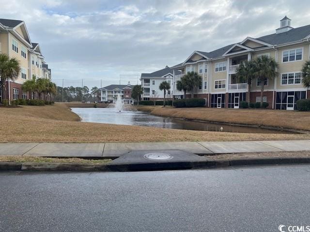 view of street with sidewalks, a residential view, a water view, and curbs