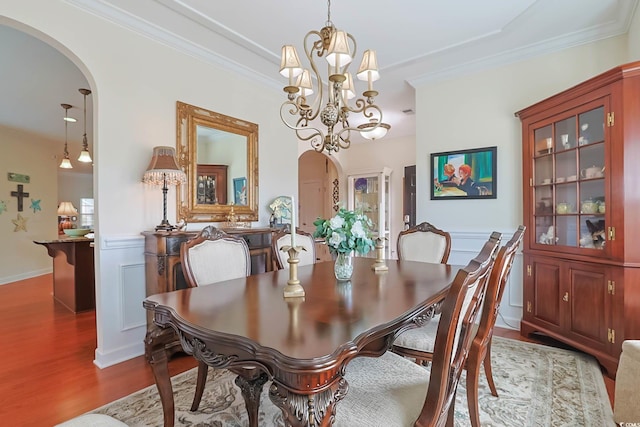 dining area featuring crown molding, wood finished floors, and arched walkways