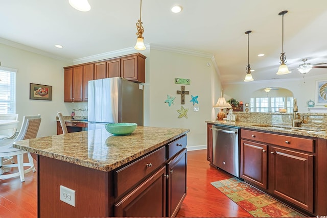 kitchen featuring a kitchen island, stainless steel appliances, crown molding, and a sink