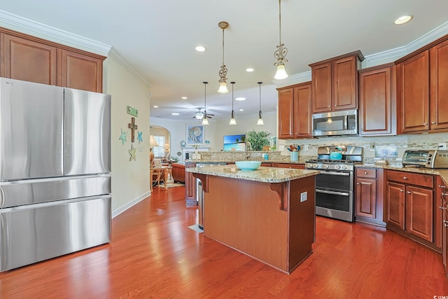 kitchen with ornamental molding, stainless steel appliances, arched walkways, a breakfast bar area, and light stone countertops