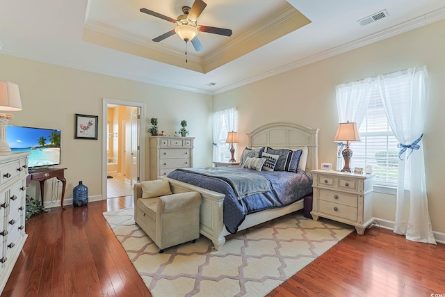 bedroom with hardwood / wood-style floors, a tray ceiling, and visible vents