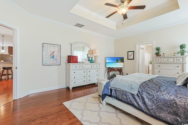 bedroom featuring visible vents, a raised ceiling, wood finished floors, and crown molding