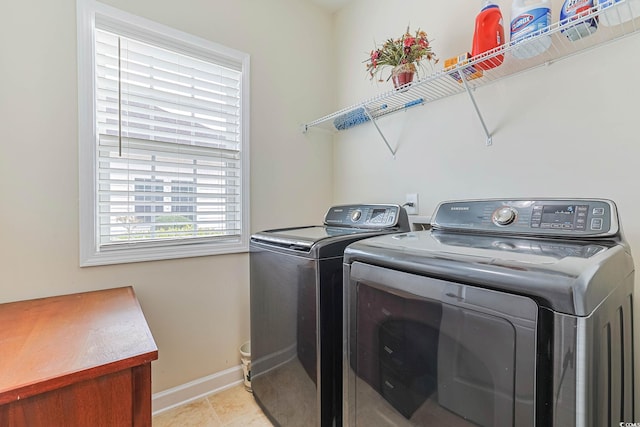 clothes washing area with washer and clothes dryer, laundry area, baseboards, and light tile patterned floors