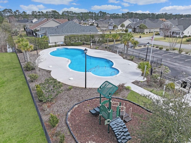 community pool featuring a yard, fence, and a residential view