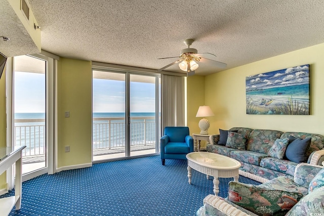 living area featuring carpet flooring, floor to ceiling windows, a ceiling fan, and a water view