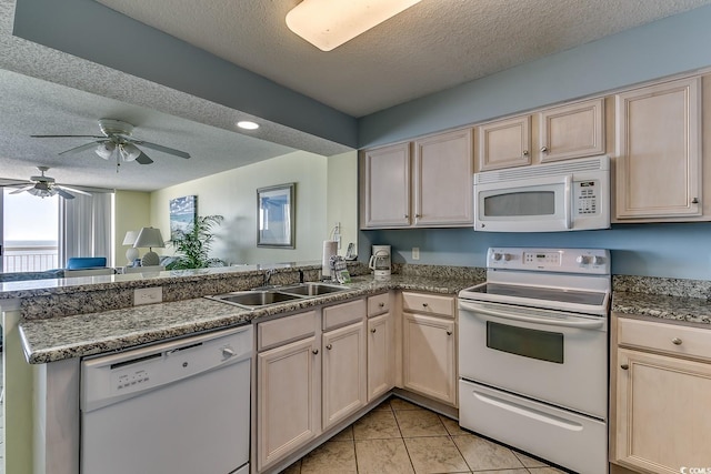 kitchen with a textured ceiling, white appliances, a peninsula, and a sink