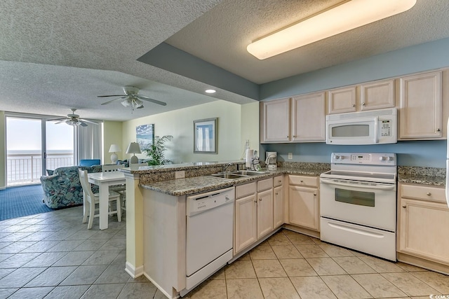 kitchen featuring a sink, a textured ceiling, white appliances, a peninsula, and light tile patterned floors