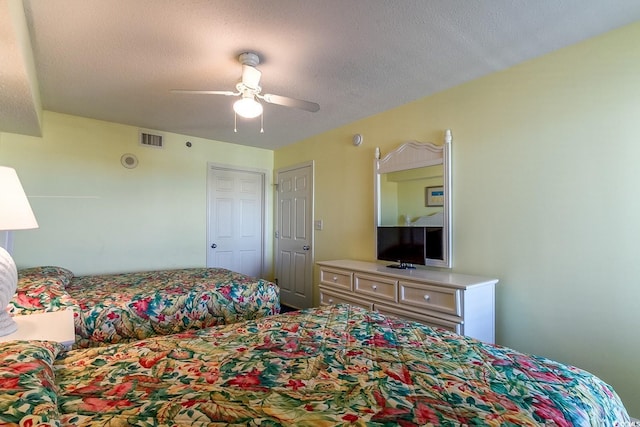 bedroom featuring visible vents, a textured ceiling, and ceiling fan