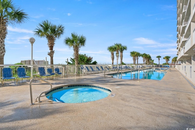 pool with a patio area and a community hot tub