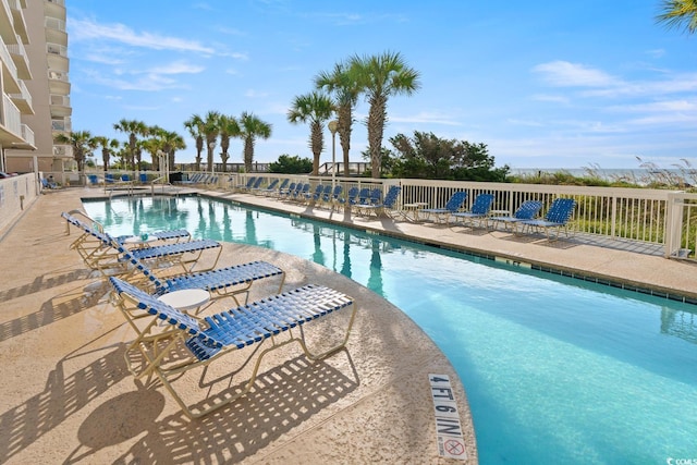 community pool with a patio area and fence