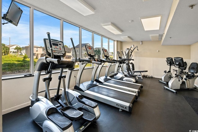 exercise room with a textured ceiling and baseboards