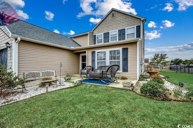 rear view of property with a yard, fence, a shingled roof, and a patio area