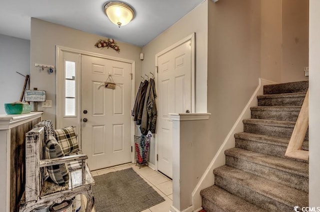 foyer featuring light tile patterned floors, baseboards, and stairs