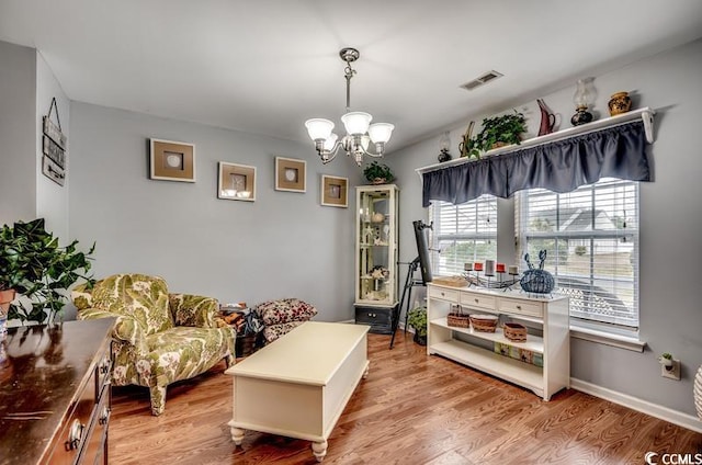 living area with visible vents, an inviting chandelier, baseboards, and light wood-style floors