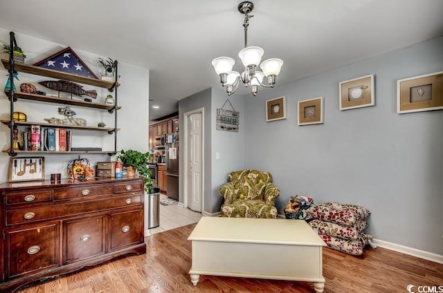 sitting room featuring baseboards, an inviting chandelier, and light wood-style flooring