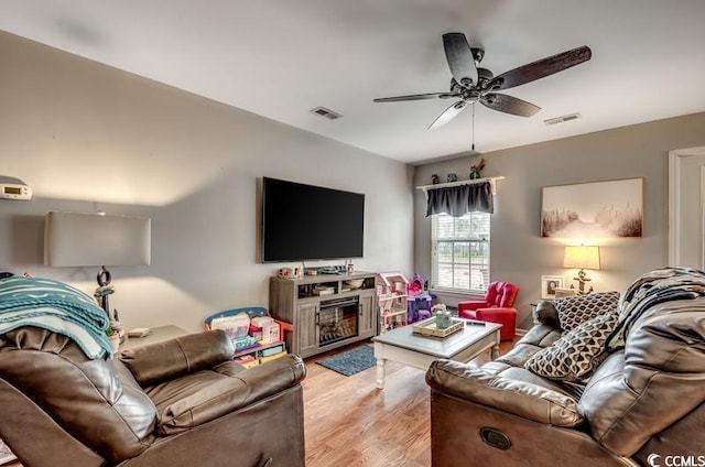 living area featuring visible vents, a ceiling fan, and light wood finished floors