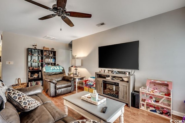 living room featuring a ceiling fan, light wood-style floors, and visible vents