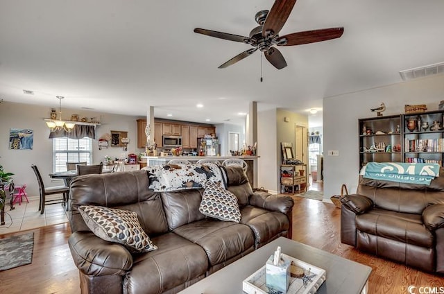 living room with recessed lighting, visible vents, light wood-style flooring, and ceiling fan with notable chandelier