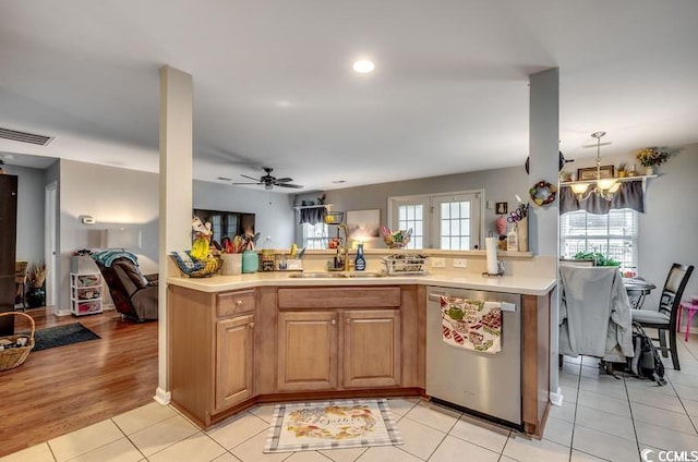 kitchen featuring a sink, stainless steel dishwasher, open floor plan, light countertops, and light tile patterned floors