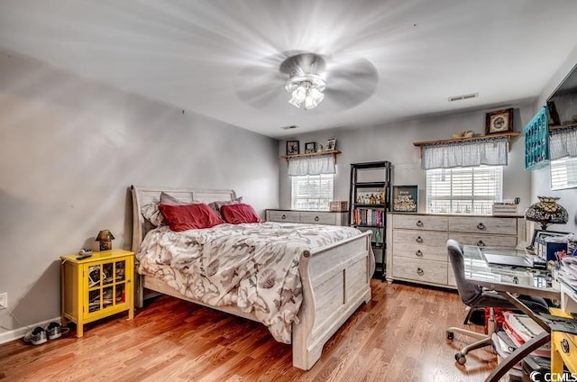 bedroom featuring multiple windows, wood finished floors, visible vents, and ceiling fan