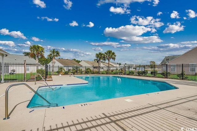 community pool featuring a residential view, a patio, and fence