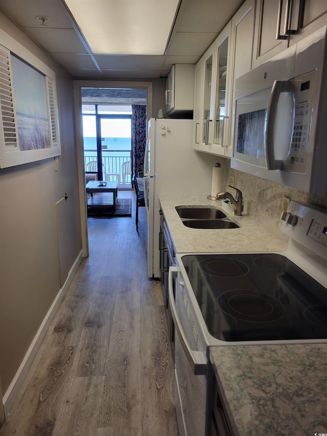 kitchen with dark wood-style floors, a sink, glass insert cabinets, range with electric stovetop, and stainless steel microwave