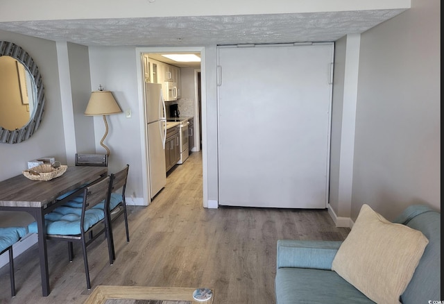 living area with light wood-style floors, baseboards, and a textured ceiling