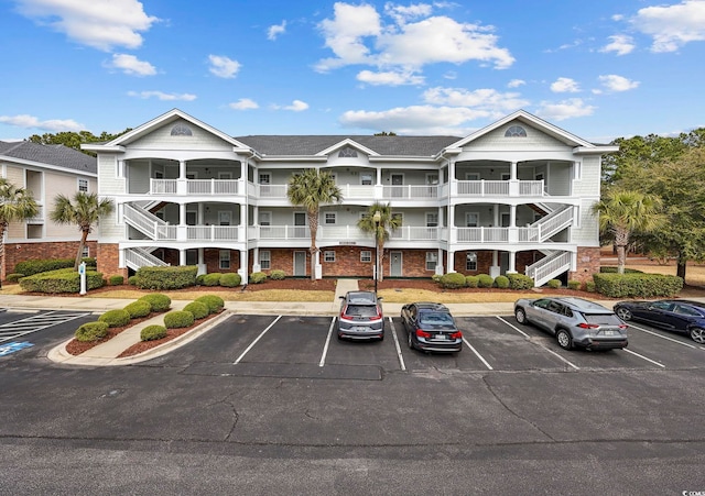 view of property featuring stairway and uncovered parking