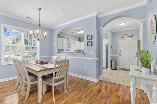 dining room featuring visible vents, a healthy amount of sunlight, light wood-type flooring, and ornamental molding