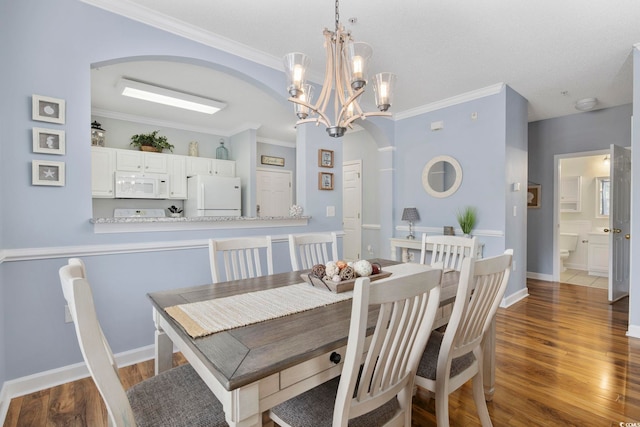 dining space with baseboards, wood finished floors, arched walkways, and ornamental molding