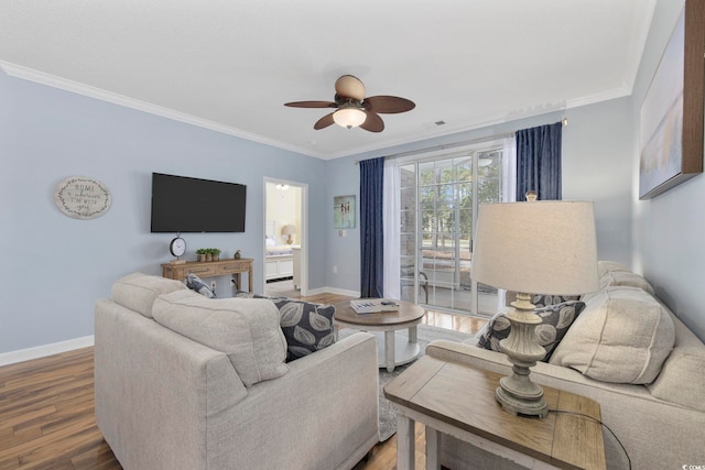 living room with a ceiling fan, crown molding, baseboards, and wood finished floors