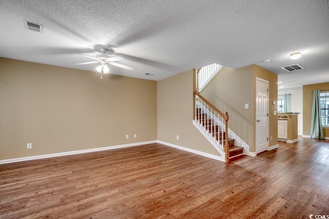 spare room with visible vents, stairway, and wood finished floors