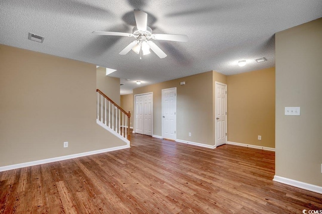 spare room with visible vents, baseboards, wood finished floors, and stairs