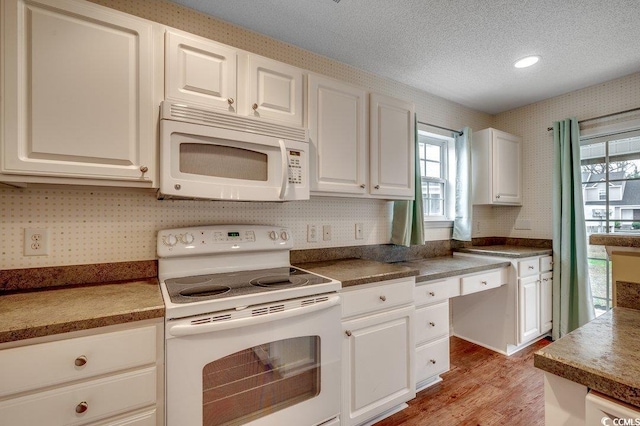 kitchen with white appliances, wallpapered walls, light wood-style flooring, a textured ceiling, and white cabinetry