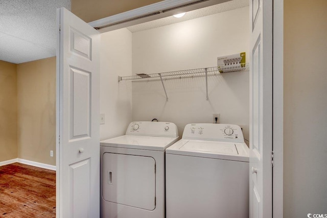 laundry area featuring laundry area, wood finished floors, independent washer and dryer, and baseboards