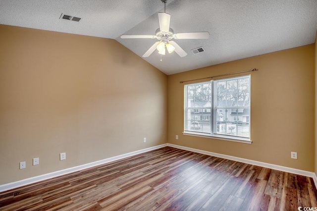 empty room with visible vents, dark wood-type flooring, baseboards, and vaulted ceiling