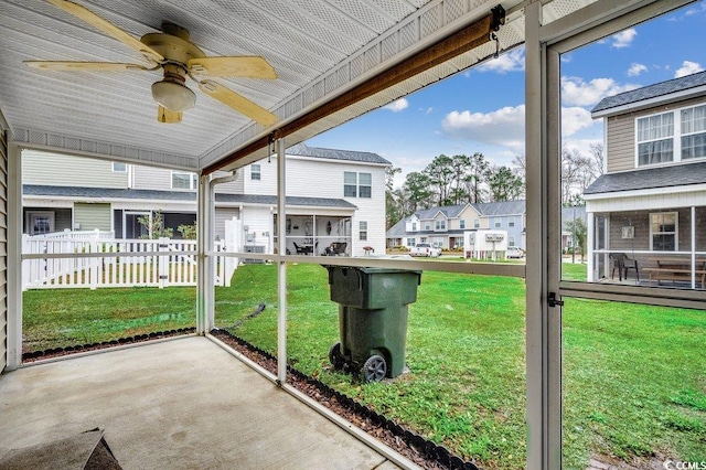 unfurnished sunroom with a ceiling fan and a residential view