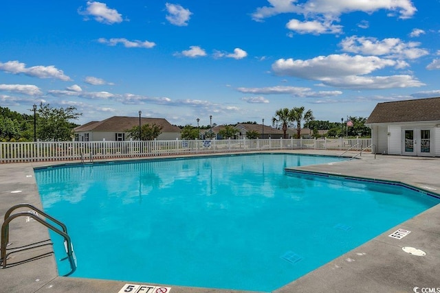 community pool with french doors, a patio, an outdoor structure, and fence