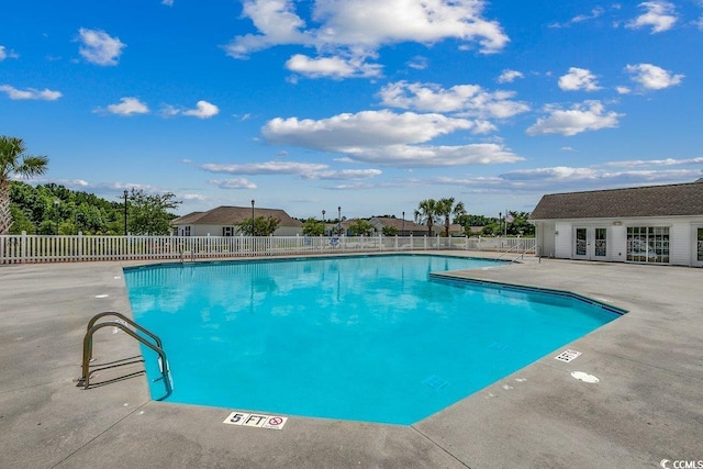 community pool with a patio, french doors, fence, and an outdoor structure