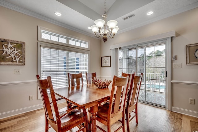 dining room featuring visible vents, a healthy amount of sunlight, light wood-style flooring, and ornamental molding