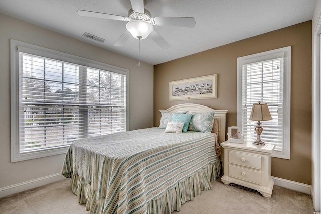 bedroom featuring visible vents, light carpet, baseboards, and ceiling fan