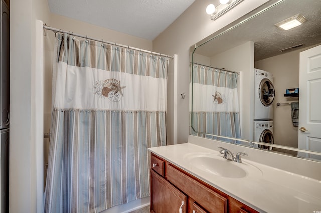 full bathroom featuring visible vents, curtained shower, vanity, stacked washing maching and dryer, and a textured ceiling