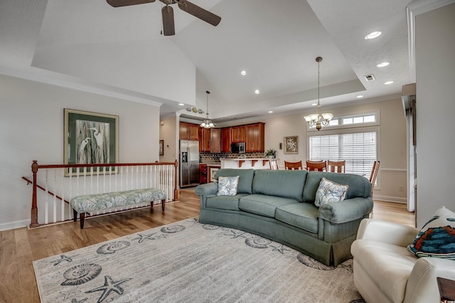 living area with visible vents, a raised ceiling, light wood-style floors, and ornamental molding