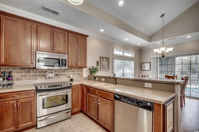 kitchen with brown cabinetry, visible vents, a peninsula, a sink, and stainless steel appliances