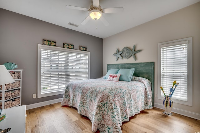 bedroom featuring a ceiling fan, visible vents, wood finished floors, and baseboards