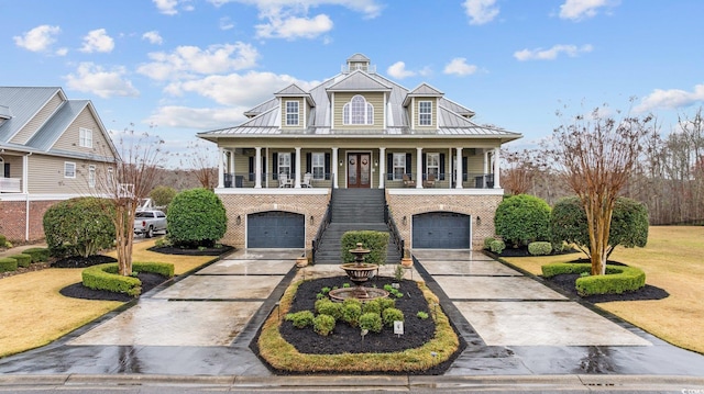 view of front of home featuring driveway, a standing seam roof, a porch, an attached garage, and stairs