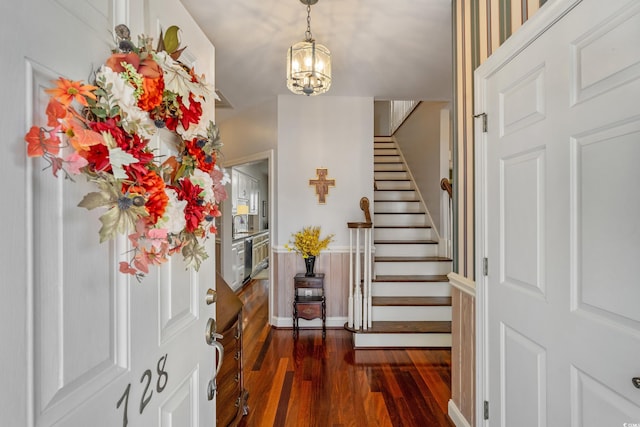 entrance foyer with dark wood-style floors, a notable chandelier, stairs, and baseboards