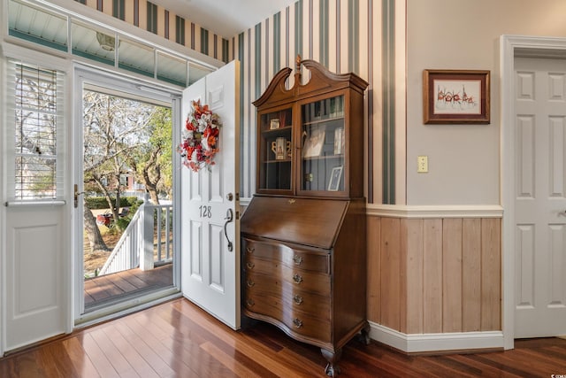 foyer entrance with baseboards, wood finished floors, and wallpapered walls