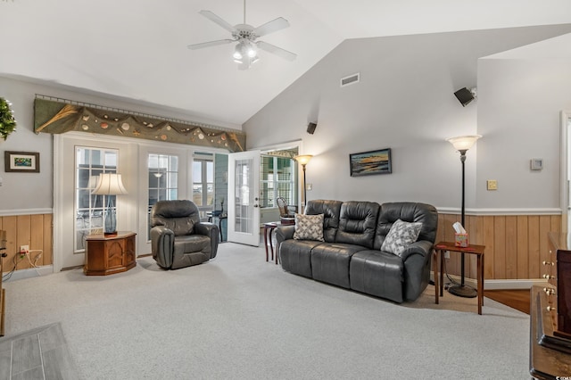 carpeted living room with visible vents, wainscoting, french doors, and wood walls